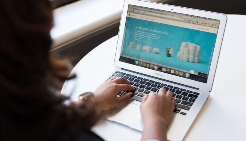 Businesswoman working on laptop with Android 6.0 Marshmallow webpage open.