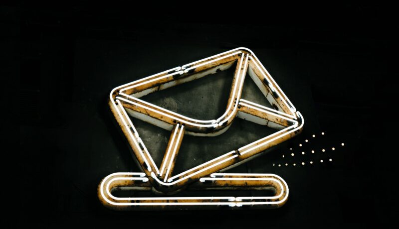 A glowing neon envelope symbol against a black background, conveying messaging or email concept.
