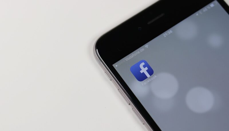 iPhone displaying Facebook app icon with blurred background, emphasizing social media connectivity.