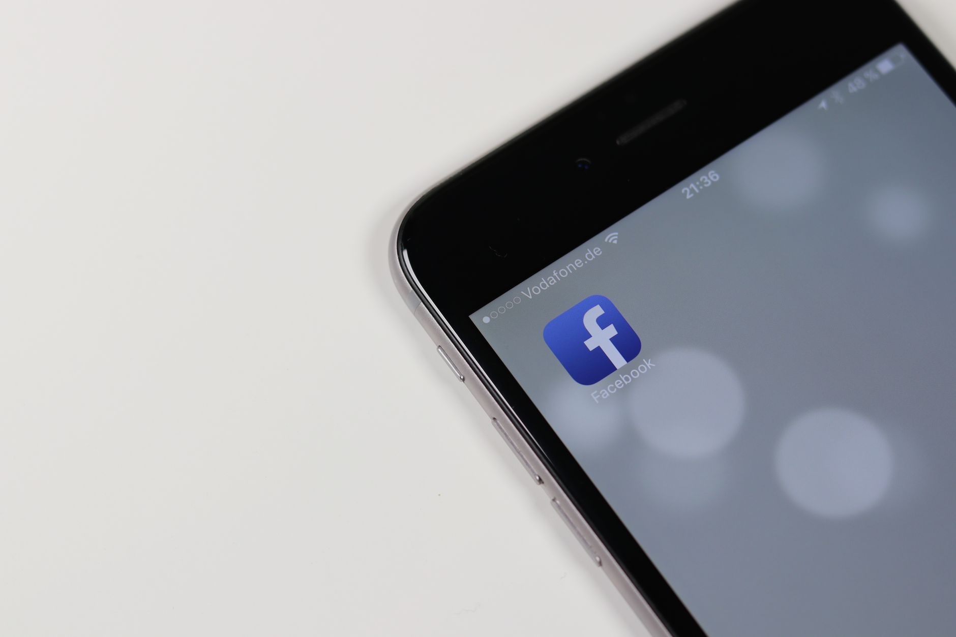 Facebook & Instagram Ads for B2B Leads: Audiences and Offers That Work 1 iPhone displaying Facebook app icon with blurred background, emphasizing social media connectivity.