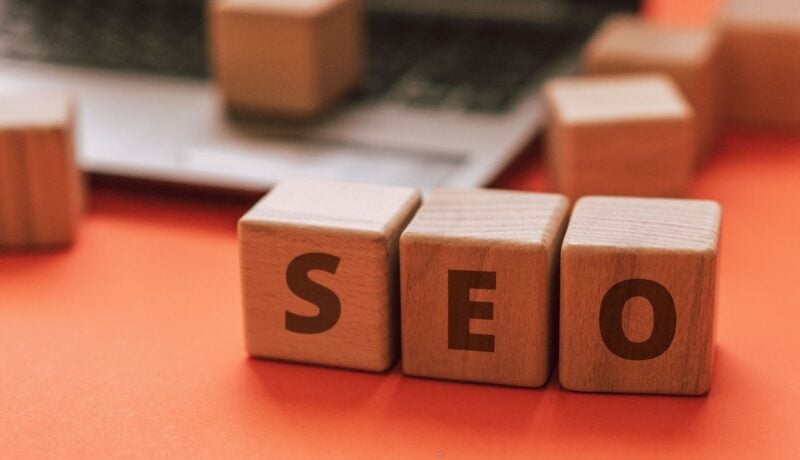 Wooden blocks spelling SEO on a laptop keyboard convey digital marketing concepts.