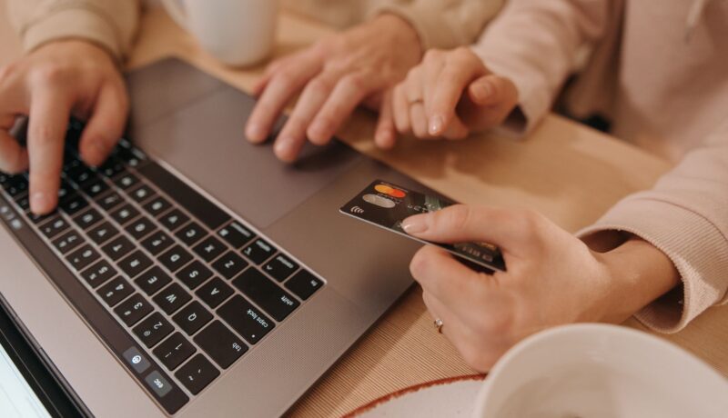 Close-up of hands using a laptop and credit card for an online payment or shopping transaction.