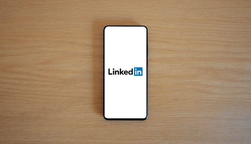 Top view of a smartphone displaying the LinkedIn logo on a wooden surface.