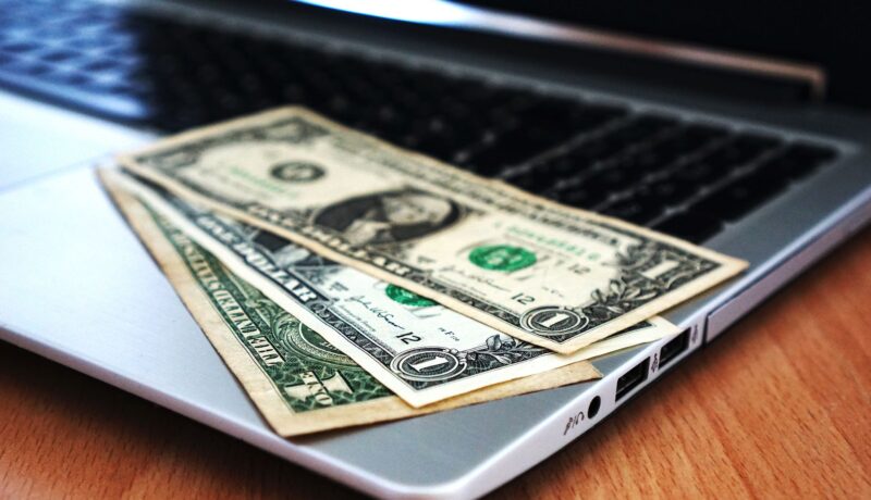Close-up of US dollar bills placed on a laptop symbolizing digital finance and economy.