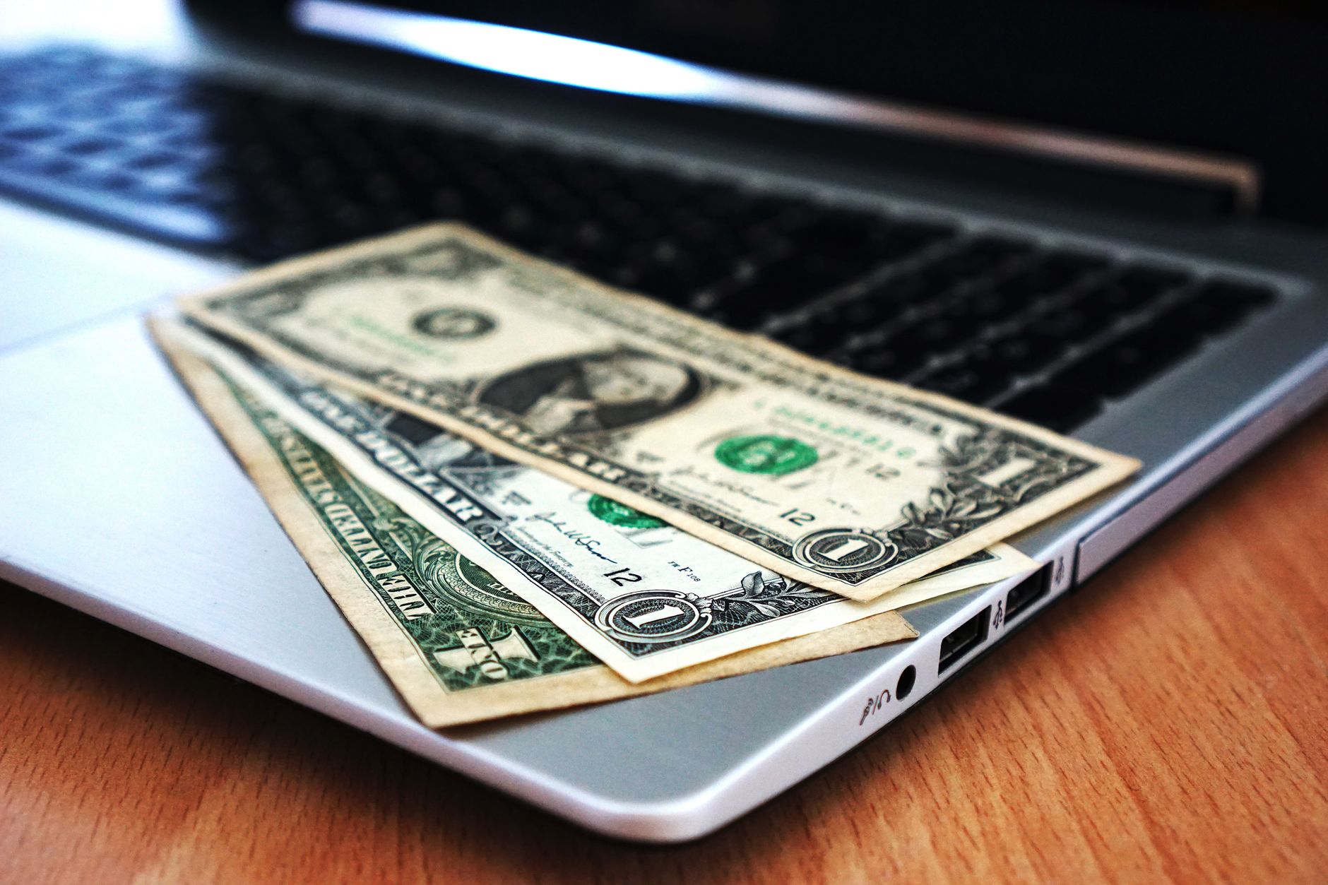 Social Ads Budget Allocation: LinkedIn vs Meta for Service Businesses 1 Close-up of US dollar bills placed on a laptop symbolizing digital finance and economy.