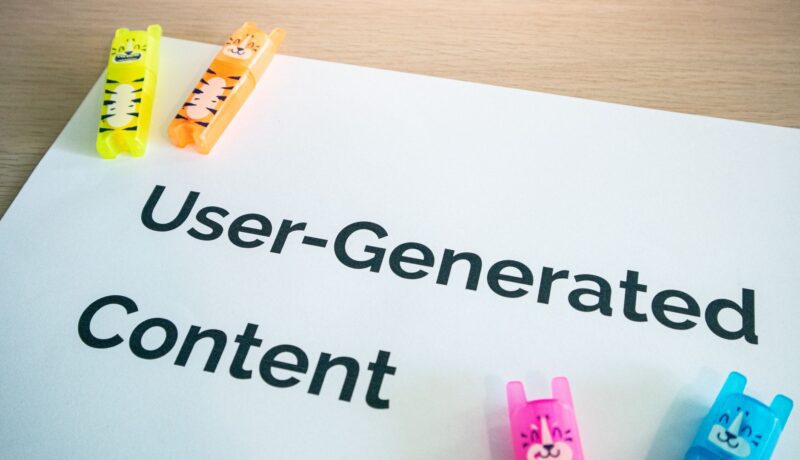 Bright highlighters on a 'User-Generated Content' note against a wooden desk.