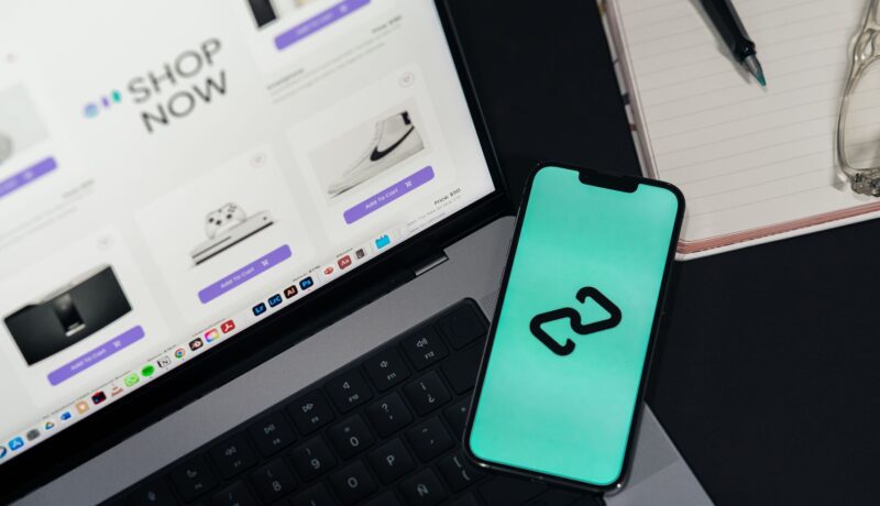 A smartphone and laptop displaying online shopping platforms, suggesting digital retail.