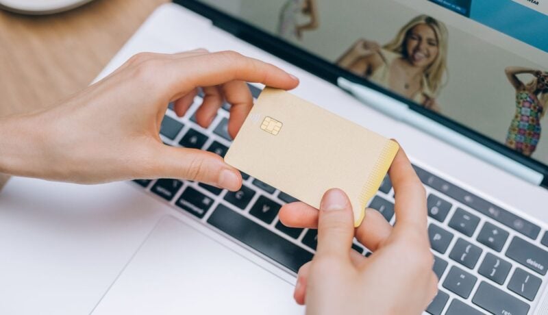 Close-up of hands holding credit card for online shopping on a laptop. Perfect for e-commerce and finance visuals.