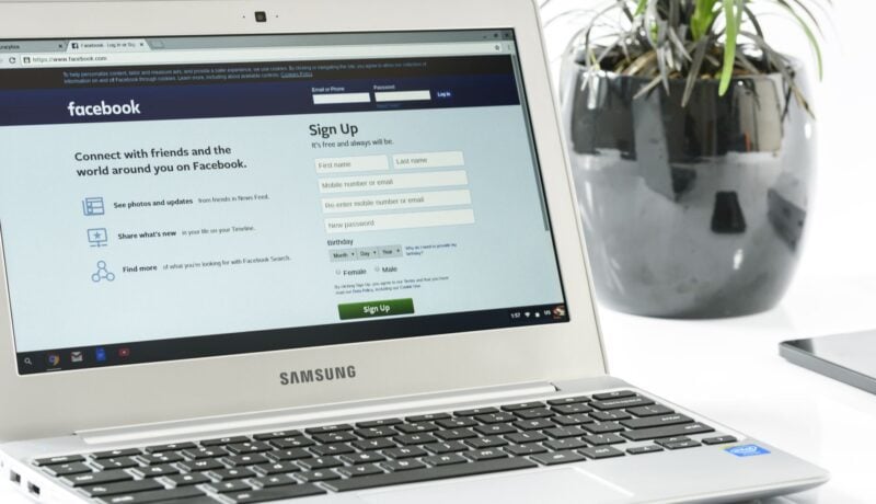 Open Samsung laptop showing Facebook sign-up page next to a potted plant. Ideal for technology themes.