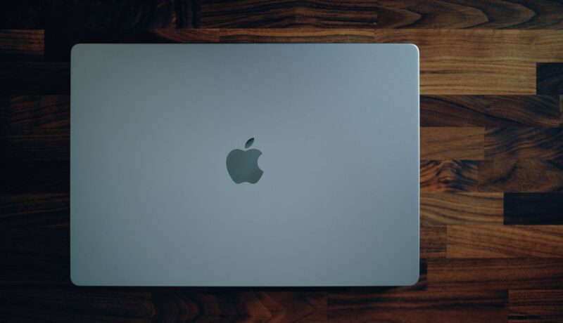 Sleek MacBook closed on a rich wooden surface, highlighting its minimalist design and modern technology.