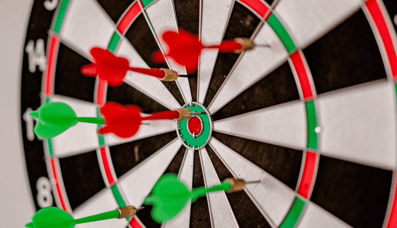 Close-up focus on darts hitting the bullseye on a dartboard, symbolizing precision and accuracy.