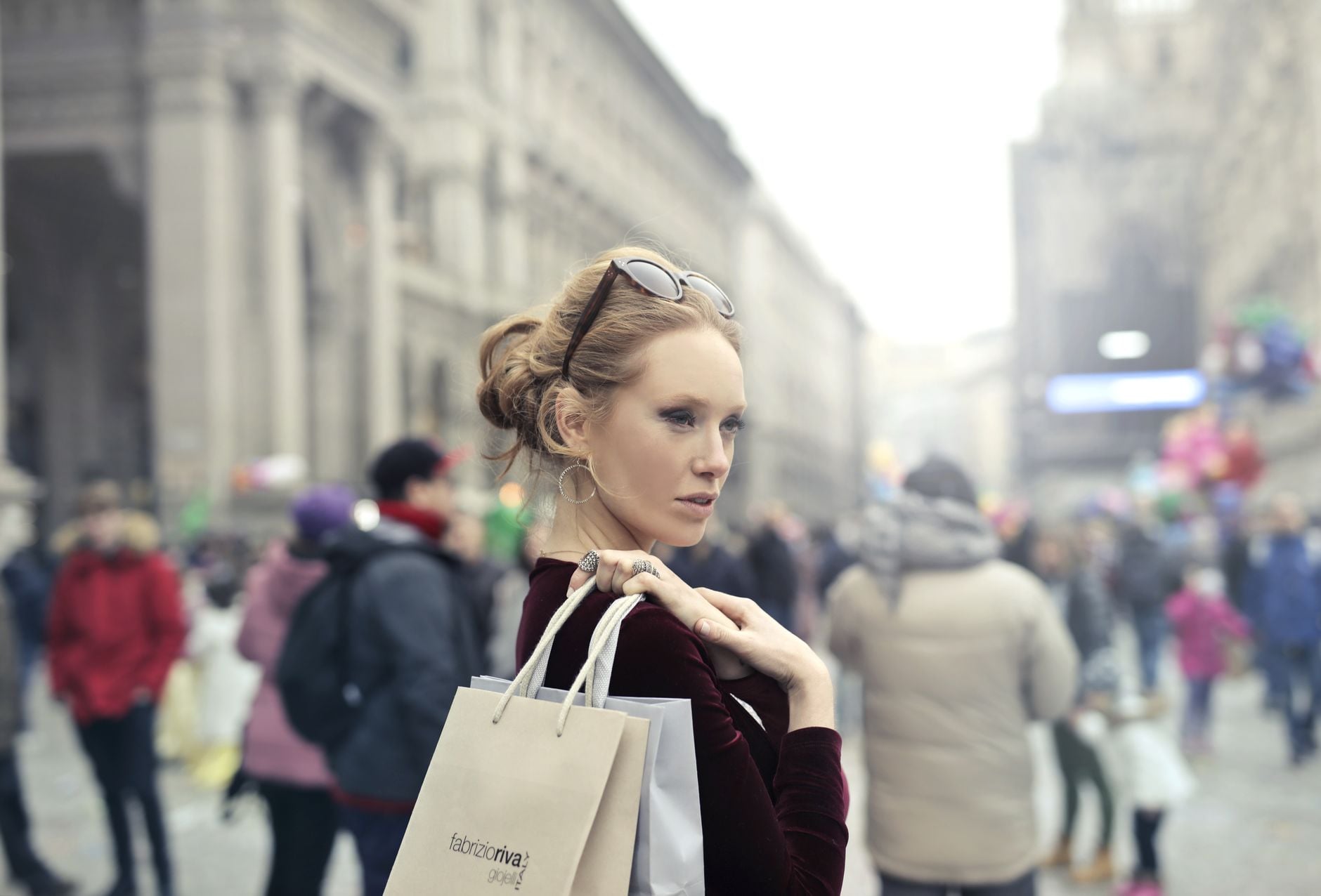 Stylish woman with shopping bags in bustling Milan street, embracing urban fashion vibes.
